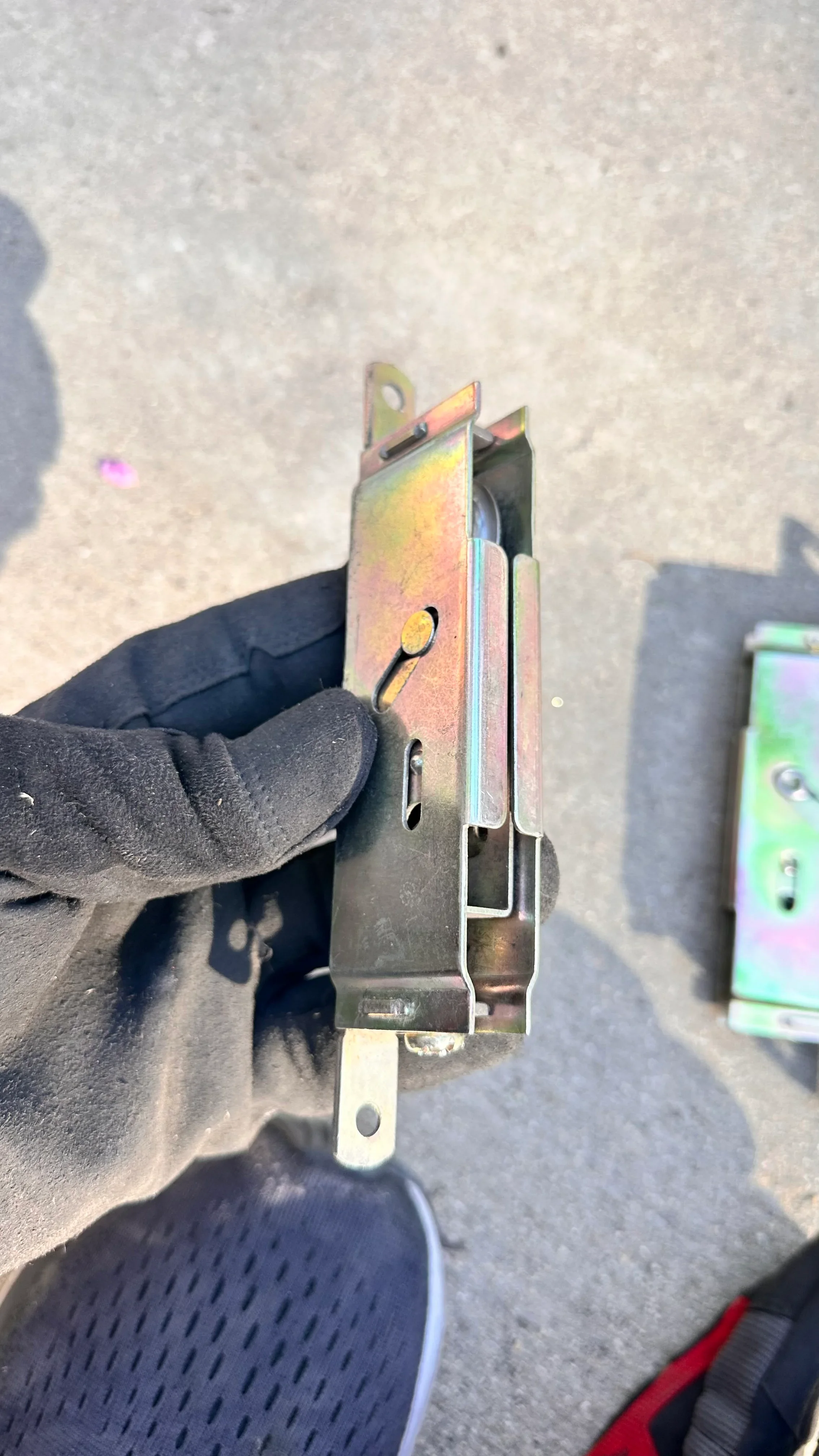 Technician inspecting commercial door closer with heat-damaged metal housing and adjustment mechanisms