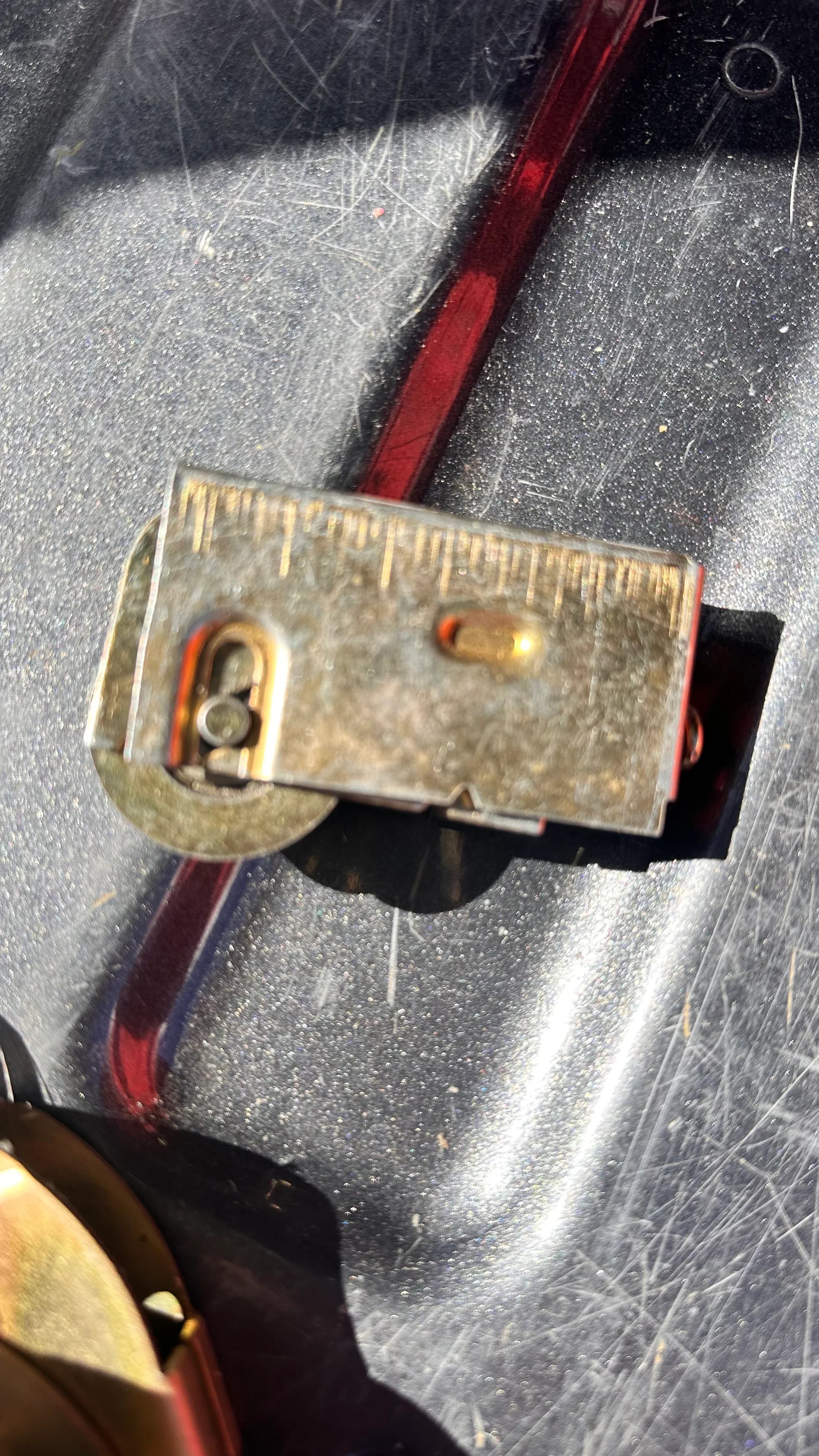 Close-up of repaired commercial door closer with brass housing and red adjustment arm
