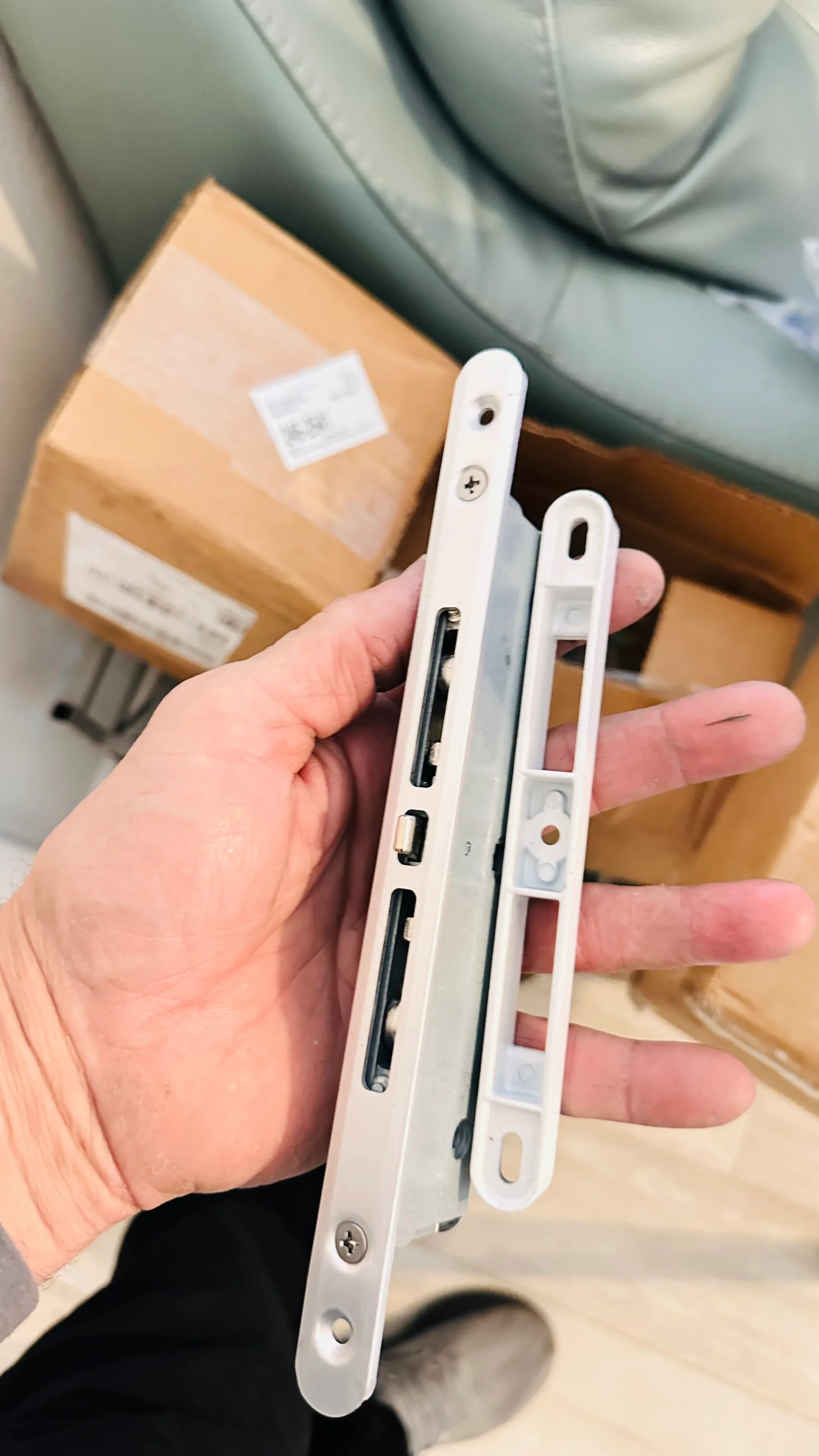 Technician holding white door latch hardware components and strike plates for inspection