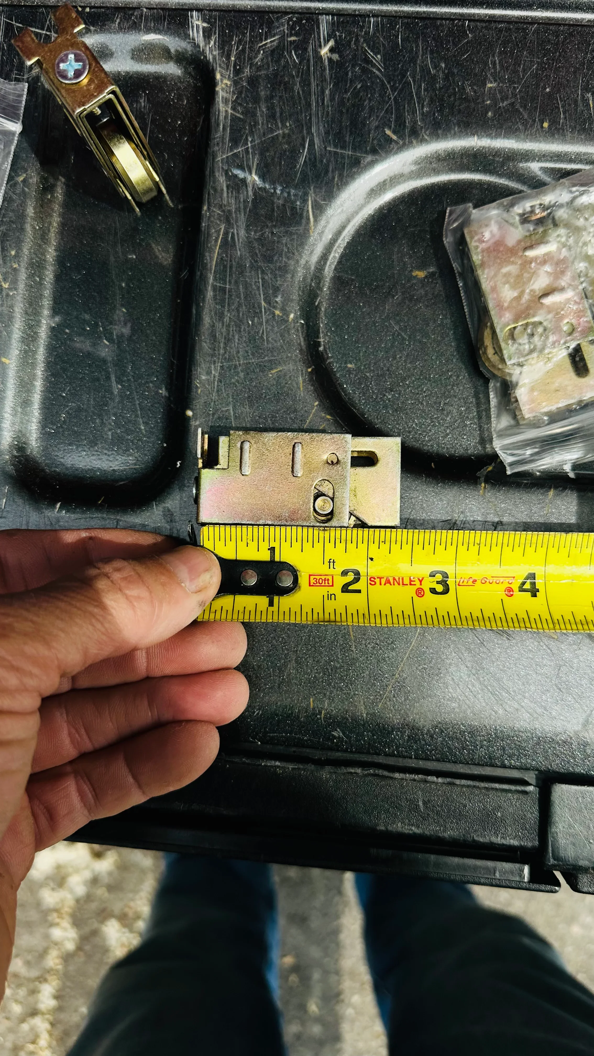 Close-up of brass door closer hardware installation with measurement tape