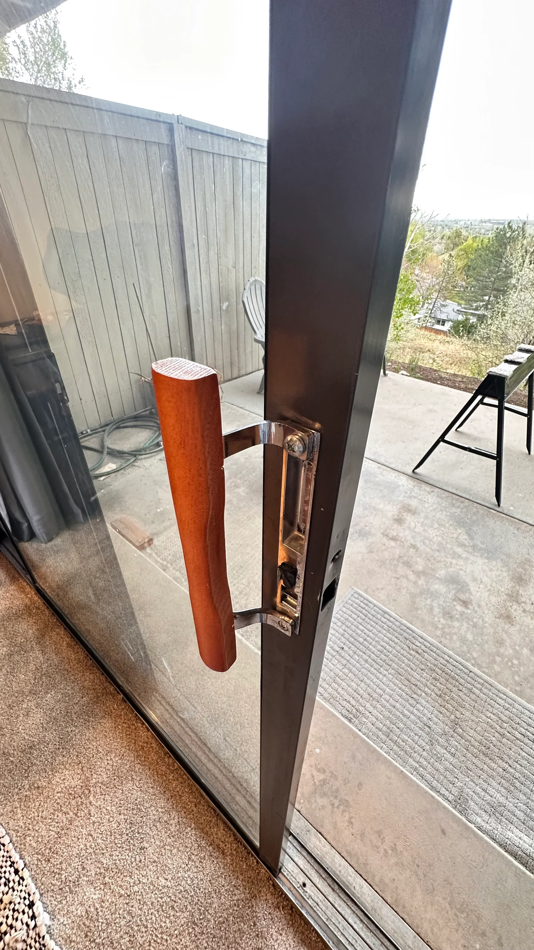Close-up of repaired sliding glass door with wood handle and chrome hardware
