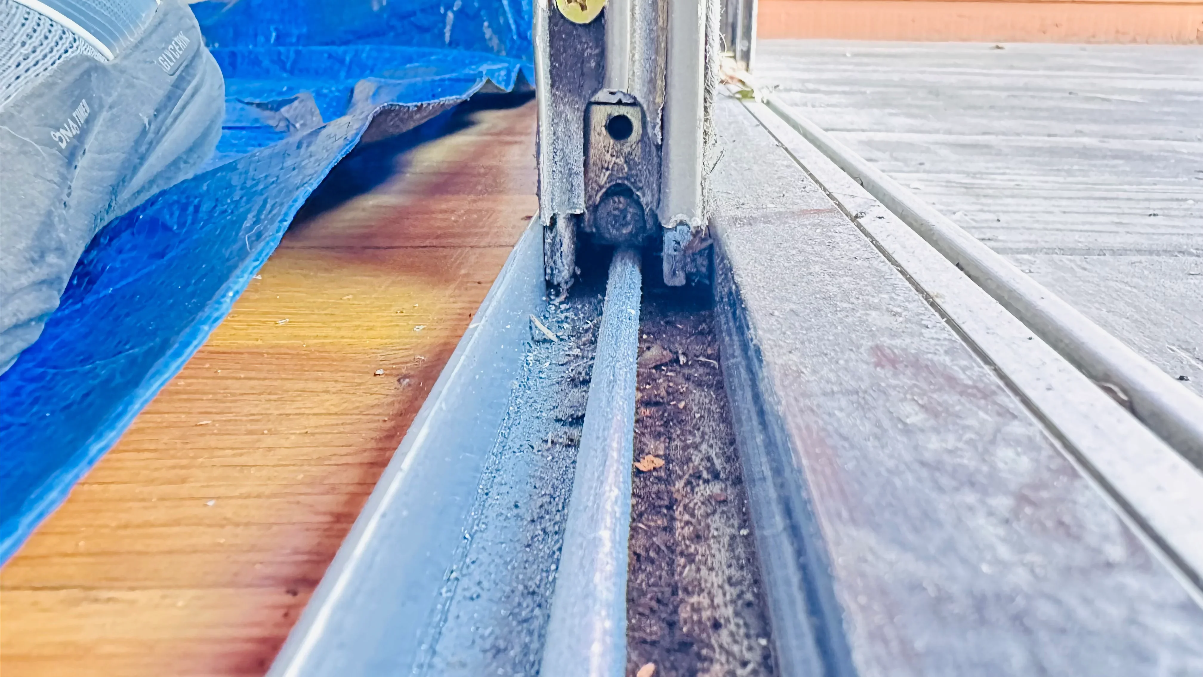 Close-up of cleaned aluminum door track with debris removal and gutter maintenance