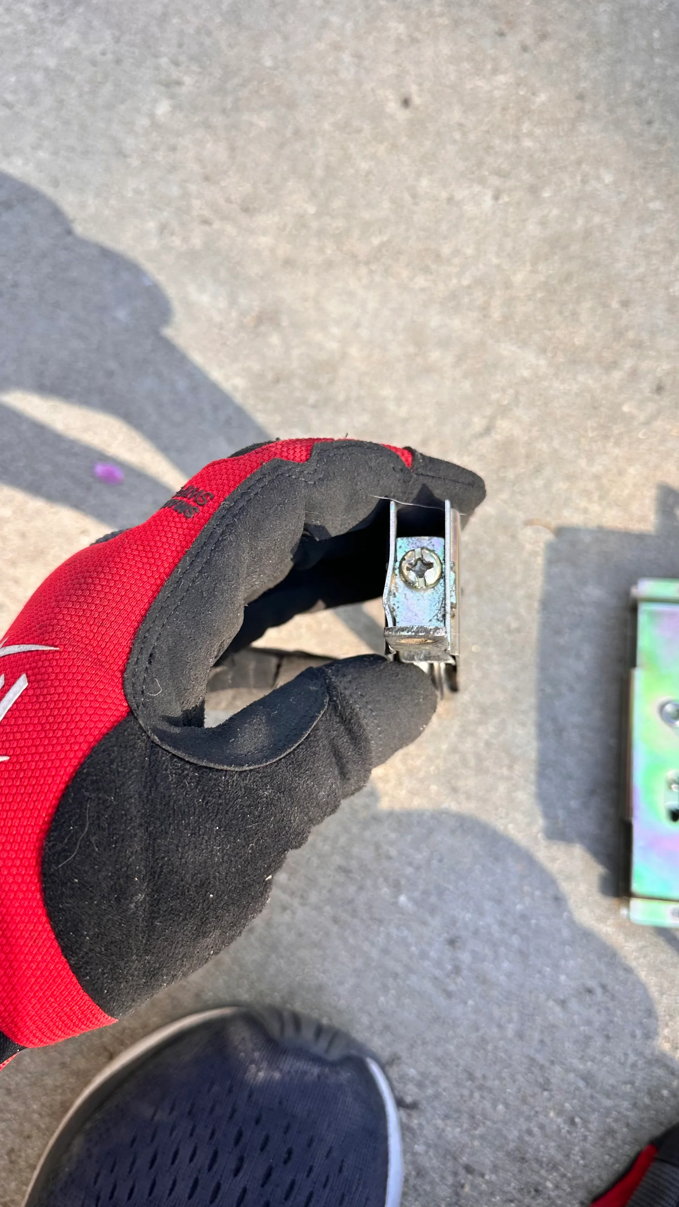 Technician in red gloves holding corroded door closer hardware during inspection