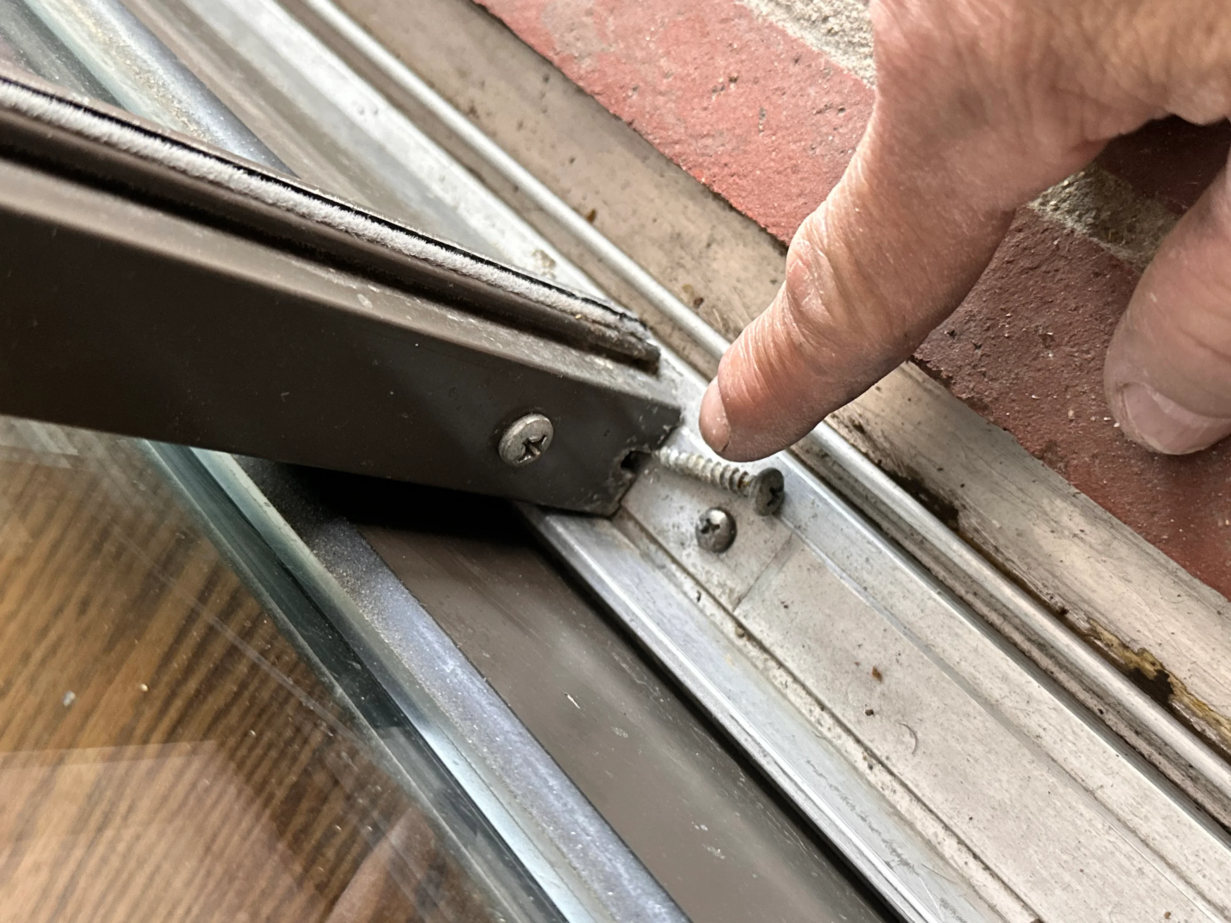 Technician installing hardware on door frame jamb with visible fasteners and wood trim