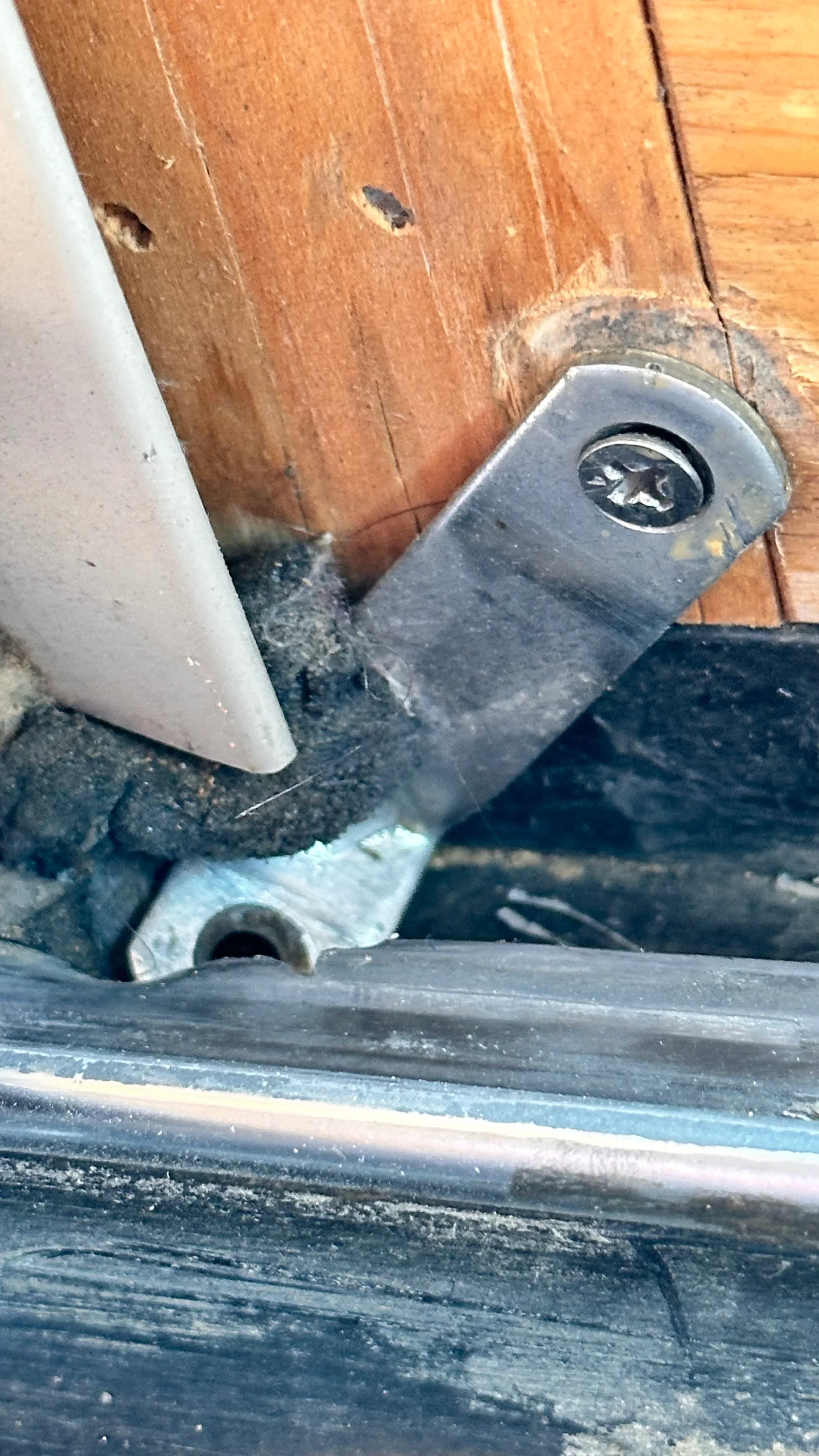 Metal door frame bracket mounted to wooden door frame with hardware detail visible