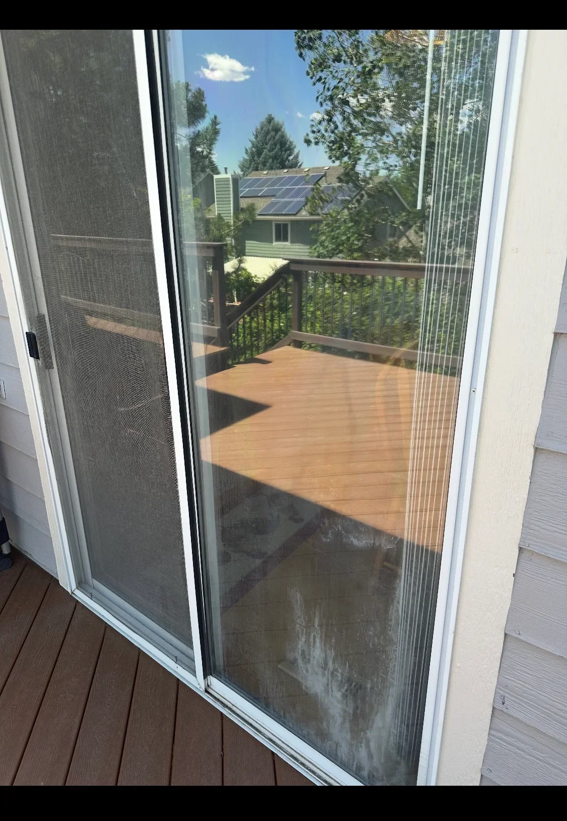 Retractable screen doors on white-framed sliding glass patio entrance overlooking wooden deck