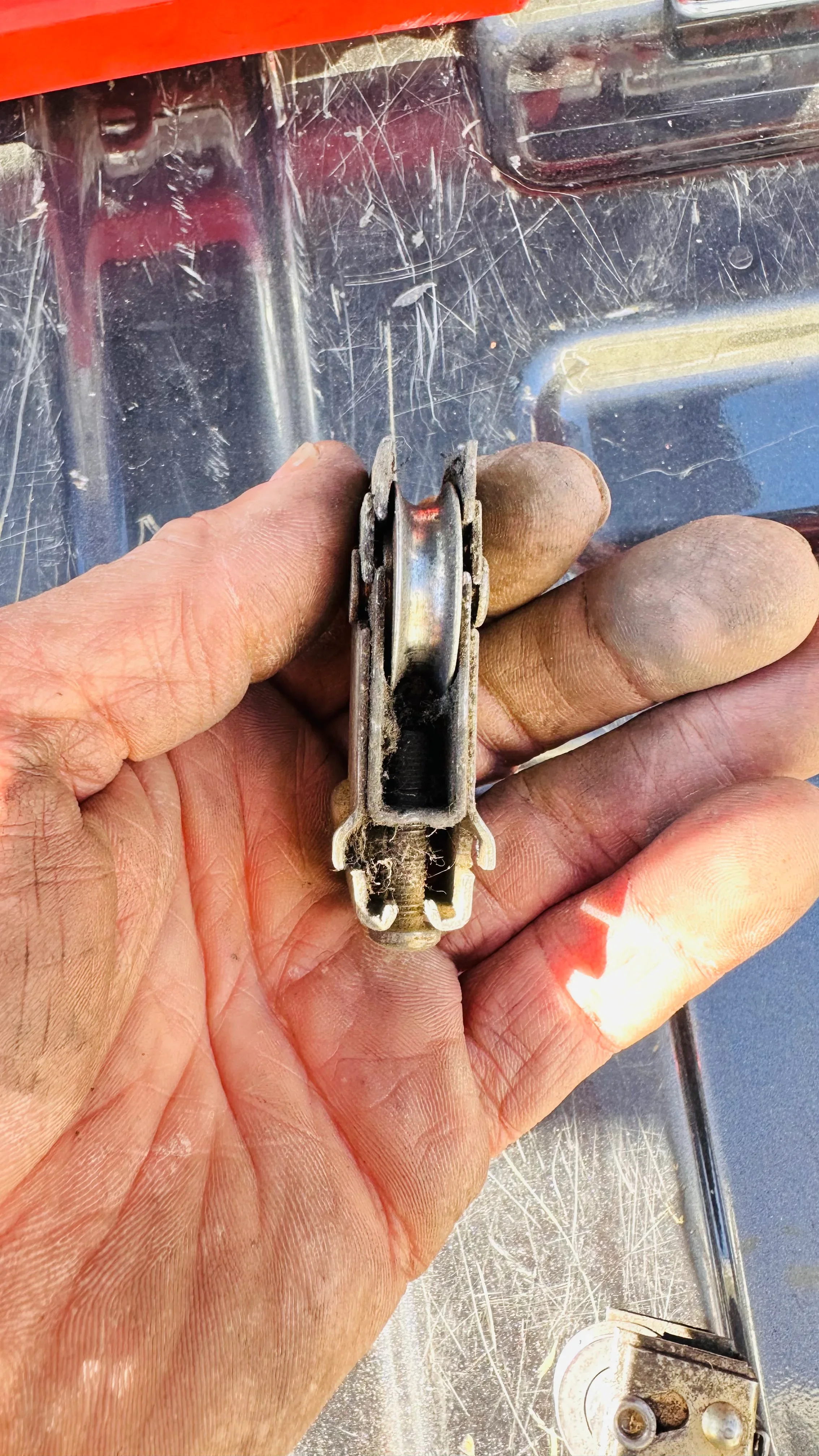 Close-up of technician holding worn metal door roller component with visible corrosion and wear damage