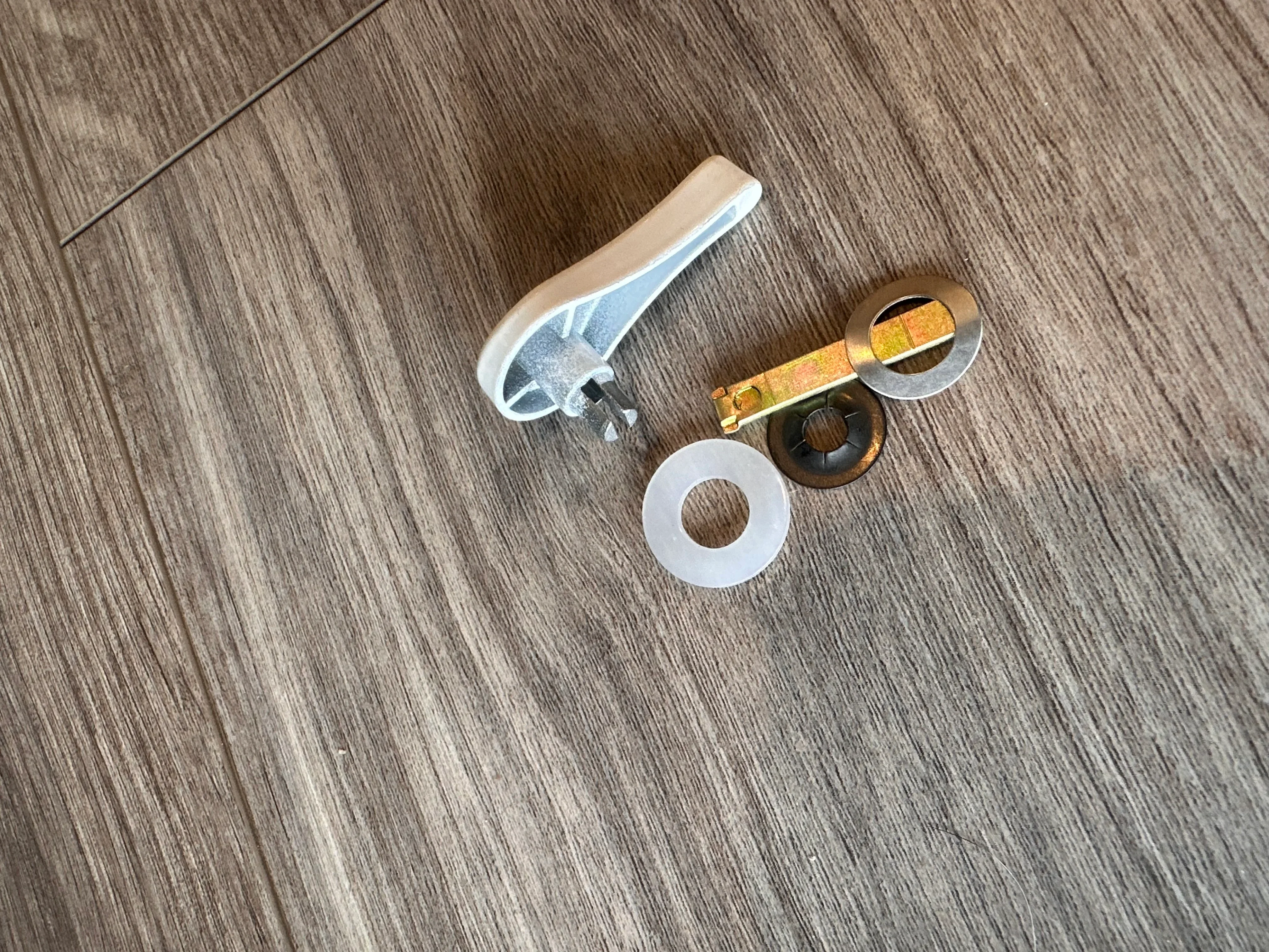 Door hardware components including lever handle, brass key, and mounting plates on wood flooring